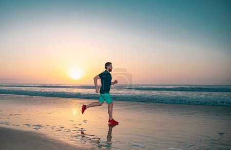 Photo for Active healthy runner jogging outdoor. Young and active jogger running. Fit male fitness runner during outdoor workout with sea sunset background - Royalty Free Image
