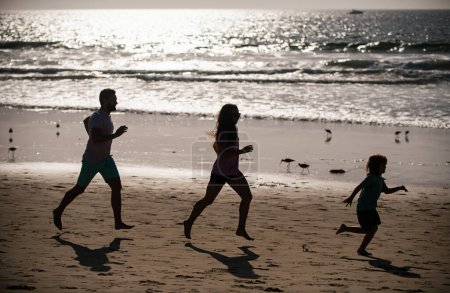 Téléchargez les photos : Silhouettes de famille de fitness courant près de la mer - en image libre de droit