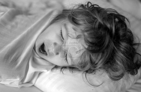 Foto de Niños tranquilos tumbados en una cama mientras duermen en un dormitorio luminoso. Despierta. Buenos días. - Imagen libre de derechos