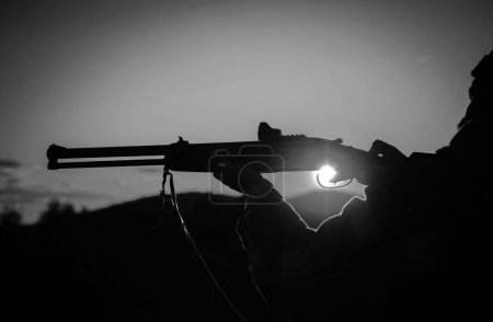 Téléchargez les photos : Calibres de fusils de chasse. Fusil Hunter Silhouette dans Beautiful Sunset. Silhouette du chasseur. J'ai appuyé sur la gâchette du fusil. Baril d'un pistolet - en image libre de droit