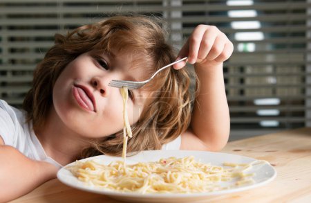 Téléchargez les photos : Portrait d'un enfant garçon mignon. Gros plan enfant caucasien manger des pâtes, spaghettis. Gros plan tête de drôles d'enfants - en image libre de droit
