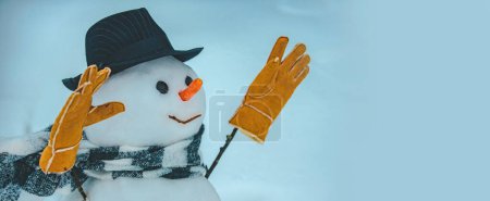Téléchargez les photos : Bannière d'hiver. Bonhomme de neige en écharpe, chapeau et gants chauds d'hiver. Joyeux Noël et Joyeuses Fêtes. Mignon petit bonhomme de neige en plein air - en image libre de droit