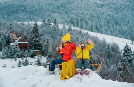 Téléchargez les photos : Des enfants en traîneau. Enfant garçon et fille joue dehors dans la neige. Hiver, vacances et Noël - en image libre de droit