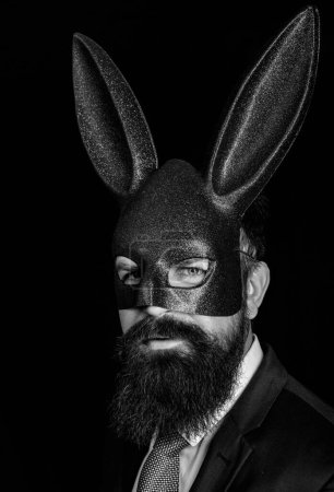 Photo for Bearded hipster in suit is ready for carnival. Funny bearded man in carnival rabbit mask. Handsome man in carnival mask ballroom rabbit with long ears sensual on a black background - Royalty Free Image