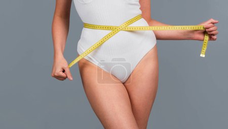 Photo for Concept of healthy eating and dieting. Young girl with perfect waist with a measuring tape. Close up - Royalty Free Image