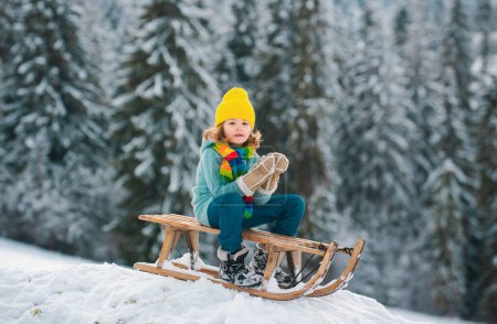 Foto de Niños felices divirtiéndose y montando el trineo en el bosque nevado de invierno, disfrutar de la temporada de invierno jugando con bola de nieve - Imagen libre de derechos