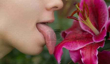 Téléchargez les photos : Langue sensuelle lécher orchidée. Femme sexy bouche avec la langue qui sort. Belle bouche close-up. Grande langue féminine. Langue sexy - en image libre de droit