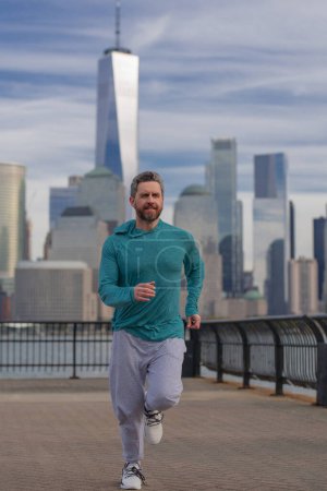 Téléchargez les photos : Homme coureur en tenue de sport courir à New York. Mouvement, course saine. Jogger court près de Manhattan. Athlète sportif musclé courir en ville. Courir des vêtements de sport. beau gars courir séance d'entraînement extérieur - en image libre de droit
