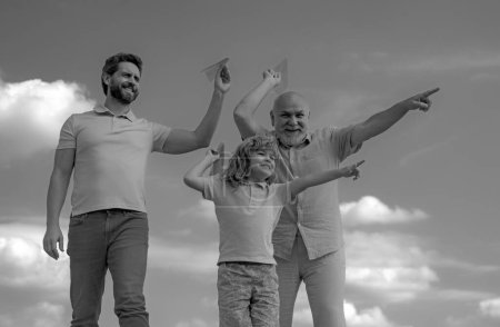 Photo for Grandfather father and son playing with paper plane outdoors on sky. Happy family. Three men generation. Happy childhood - Royalty Free Image