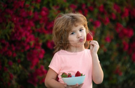 Photo for Kids funny face. Cute child eating strawberries - Royalty Free Image