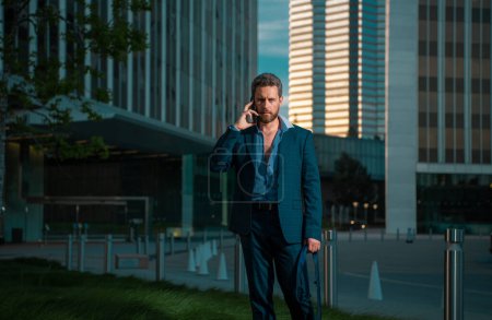 Téléchargez les photos : Homme d'affaires avec téléphone debout et fond de ville de nuit - en image libre de droit