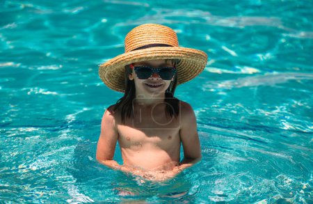 Téléchargez les photos : Un gamin nage dans la piscine. Activités estivales et de natation pour les enfants sur la piscine. Enfants actifs mode de vie sain, activité de sport nautique et cours de natation en vacances d'été avec enfant - en image libre de droit