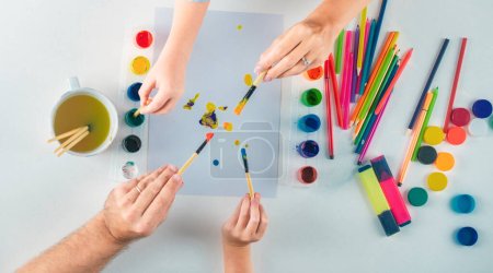 Foto de Top view suministros de arte. La mano humana de la madre padre y los niños está dibujando con lápices de colores. Niños aprendiendo pintura - Imagen libre de derechos