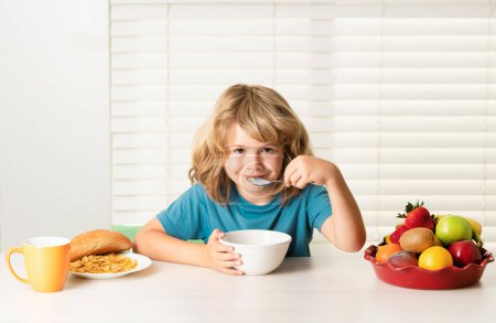 Téléchargez les photos : Enfant pré-adolescent garçon 7, 8, 9 ans mangeant des légumes sains. Petit déjeuner avec lait, fruits et légumes. Manger un enfant pendant le déjeuner ou le dîner à la maison - en image libre de droit