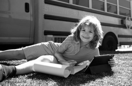 Foto de Retrato de un colegial escribiendo al aire libre en el parque escolar y haciendo los deberes - Imagen libre de derechos