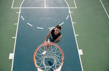 Téléchargez les photos : Jeune sportif jouant au basket-ball en plein air sur le terrain de basket - en image libre de droit