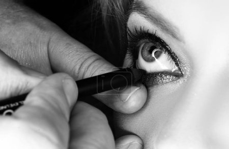 Foto de Maquilla los ojos. Primer plano de los ojos. Aplicación de eyeligner, maquillaje vadage - Imagen libre de derechos