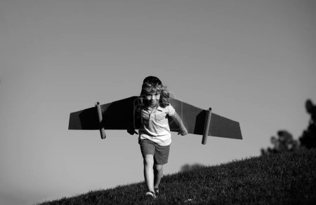 Photo for Child playing with cardboard toy wings in the park. Concept of children day. Kid boy in an pilot costume is playing and dreaming of becoming a aviator spaceman. Kids freedom concept - Royalty Free Image