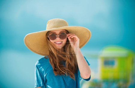 Téléchargez les photos : Gros plan portrait d'une femme souriante au bord de la mer. Femme heureuse en lunettes de soleil et chapeau de paille debout au bord de la mer - en image libre de droit