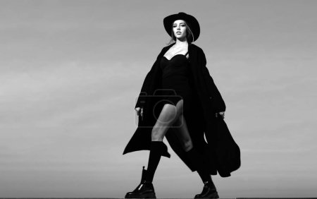 Téléchargez les photos : Femme de mode en manteau de mode noir, chapeau et chaussures noires bottes - en image libre de droit