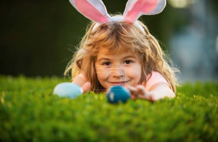 Photo for Kids boy hunting easter eggs. Child in bunny ears on Easter egg hunt in garden - Royalty Free Image