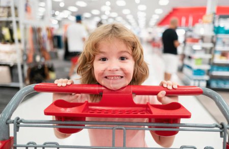 Téléchargez les photos : Enfant avec panier à provisions achetant de la nourriture dans une épicerie. Clients enfants achetant des produits au supermarché - en image libre de droit