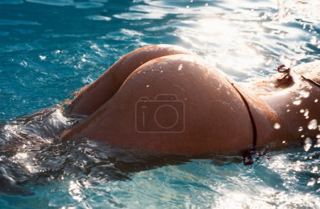 Téléchargez les photos : Femme fesse gros plan en bikini. Vacances d'été. Partie du corps de mince et en forme jeune fille sur fond d'eau de mer - en image libre de droit