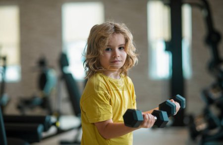 Photo for Kid workout kid in gym. Sport activities at leisure with children. Blonde boy holding dumbbells. Sports exercises for children. Funny child lifting the dumbbells - Royalty Free Image