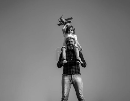 Photo for Father carrying his son on shoulders. Father and son playing with toy plane outdoor. Family holiday, parenthood. Fathers day - Royalty Free Image