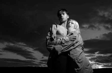 Téléchargez les photos : Jeune couple amoureux s'étreignent sur un ciel dramatique. Histoire d'amour - en image libre de droit