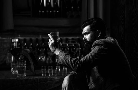 Photo for Handsome bearded man enjoying whiskey in bar. Hipster jacket drinking a brandy in bar. Brutal guy drinking alcohol. - Royalty Free Image
