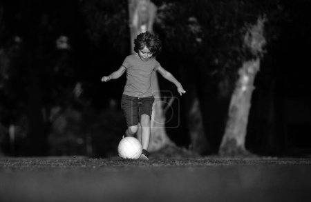 Téléchargez les photos : Un gamin de foot. Les enfants jouent au football sur le terrain de stade extérieur. Un petit garçon qui donne des coups de pied. Club de football scolaire. Formation pour les enfants sportifs. Enfant footballeur dans le parc - en image libre de droit