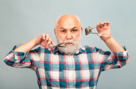 Foto de Retrato de hombre con estilo barbudo hombre con bigote gris barba agarre tijeras y afeitadora de pelo liso - Imagen libre de derechos