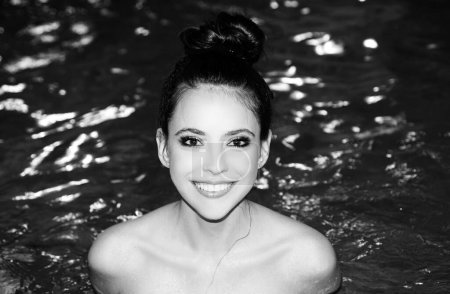Foto de Retrato de moda de cerca de una chica feliz y sonriente en la piscina. Mujer posando sobre el fondo azul del agua - Imagen libre de derechos