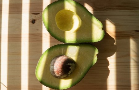 Foto de Avocado fruit. Raw Fruits healthy green food. Half avocado. Avocado on wooden background - Imagen libre de derechos
