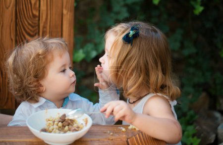 Photo for Baby food, babies eating. Little girl sister feeding baby - Royalty Free Image