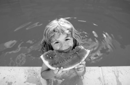 Téléchargez les photos : Enfant avec pastèque souriant nageant dans la piscine en été sur place. Enfants avec morceau de melon d'eau en plein air. Vacances d'été et concept de saine alimentation - en image libre de droit