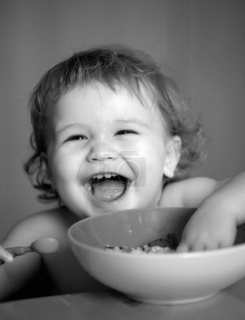 Foto de Lanzar a un niño comer. Bebé sonriente comiendo comida. Concepto de familia, alimentación, niño, alimentación y paternidad - Imagen libre de derechos