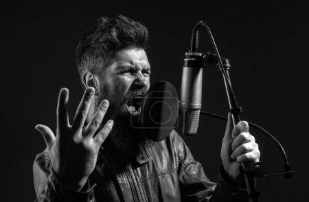 Foto de Un hombre guapo en el estudio de grabación. Interpretación musical vocal. Cantante cantando canción con un micrófono - Imagen libre de derechos