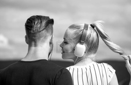 Téléchargez les photos : Charmant couple écoutant de la musique. Se détendre à l'extérieur ensemble. Concept de relations - en image libre de droit