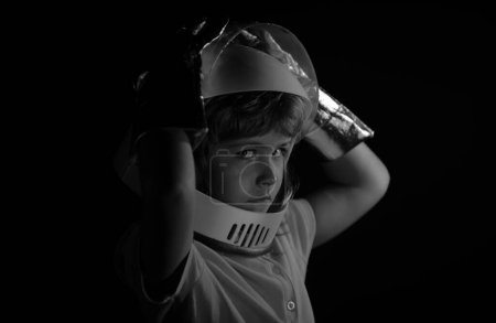 Téléchargez les photos : Gros plan portrait d'enfants isolés sur noir, imagination aventure. Enfant garçon jouant astronaute avec astronaute - en image libre de droit