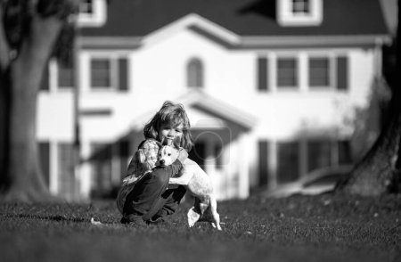 Foto de Mascotas y amistad humana. Niño lindo se siente encantado, lleva pequeño perro bebé, expresa emociones tiernas, cuidado y amor a cachorro pequeño - Imagen libre de derechos