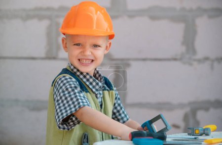 Photo for Child in building helmet, hard hat. Repair home. Child dressed as a workman builder. Portrait little builder in hardhats. Little builder in helmet - Royalty Free Image