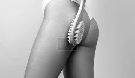 Téléchargez les photos : Woman legs with clean skin. Female buttocks ass without cellulite. Brushing skin buttocks and butt with a dry wooden brush to prevent and treatment cellulite and body problem - en image libre de droit