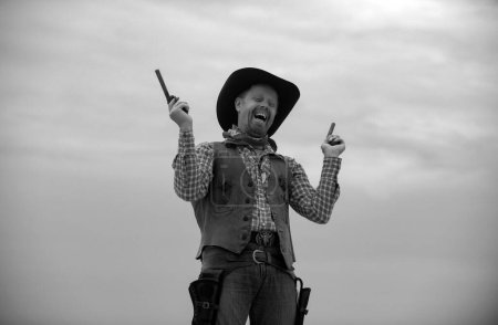 Téléchargez les photos : Voulait western. Joyeux cow-boy drôle avec une arme. Bandit américain, homme occidental avec chapeau. Ouest et armes - en image libre de droit