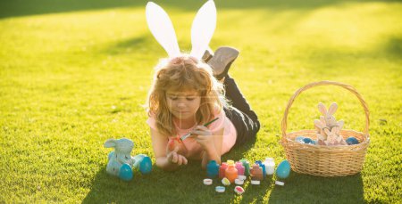 Foto de Feliz conejito de Pascua niño pintando huevos. Primavera niños vacaciones concepto - Imagen libre de derechos