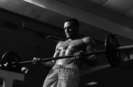 Photo for Muscular man doing crossfit. Fit man doing biceps lifting barbell. Young man working out at crossfit gym. Athletic guy doing exercise - Royalty Free Image