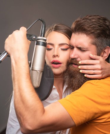 Téléchargez les photos : Un chanteur et une chanteuse dans un studio. Couple sensuel avec microphone. Signataire karaoké, chanteur musical - en image libre de droit