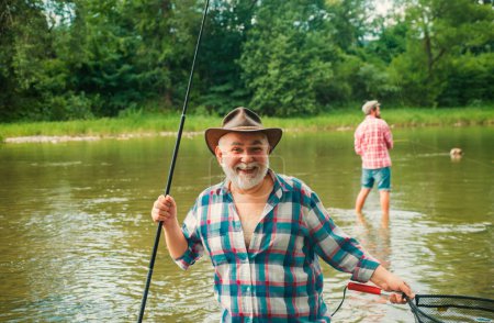 Photo for Portrait of cheerful senior man fishing. Grandfather and son fishermans. Young man and an old man fishing for spinnings on the river or lake - Royalty Free Image