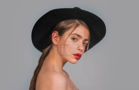 Photo for Young woman with make up and black hat in black studio. Fashion portrait of female model with red lips - Royalty Free Image